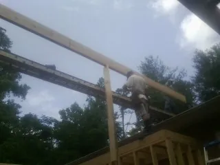 Carpenter setting a ridge beam over a new addition frame — Ice Dam Removal by Roofing Brothers in Prompton