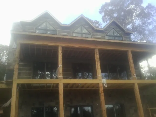 Dormers and porch framing on a large log home under construction — Roof Coating work by our crew in Prompton