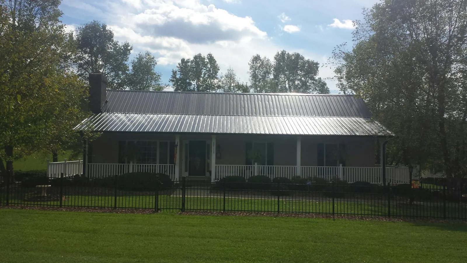 Gray metal roof on a brick ranch with a full width front porch — Gutter Guard Installation work by our crew in Prompton