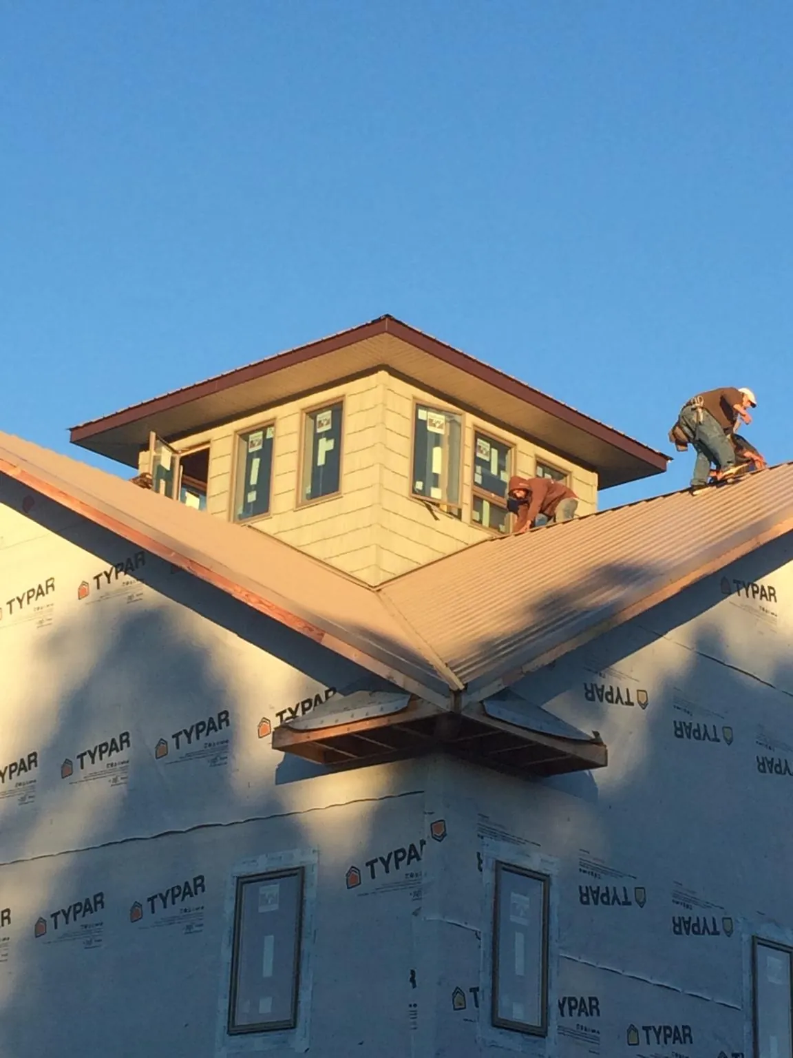 Roofers working around a rooftop cupola on a new metal roof at sunset — Roof Waterproofing in Prompton by Roofing Brothers